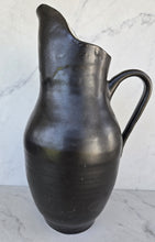 Load image into Gallery viewer, Matte black pitcher with a pulled spout, a curved handle and a rounded lower body.