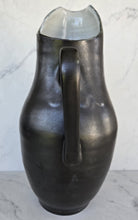 Load image into Gallery viewer, Matte black pitcher with a glossy interior spout, a curved handle attached along the side, and a tall rounded body.