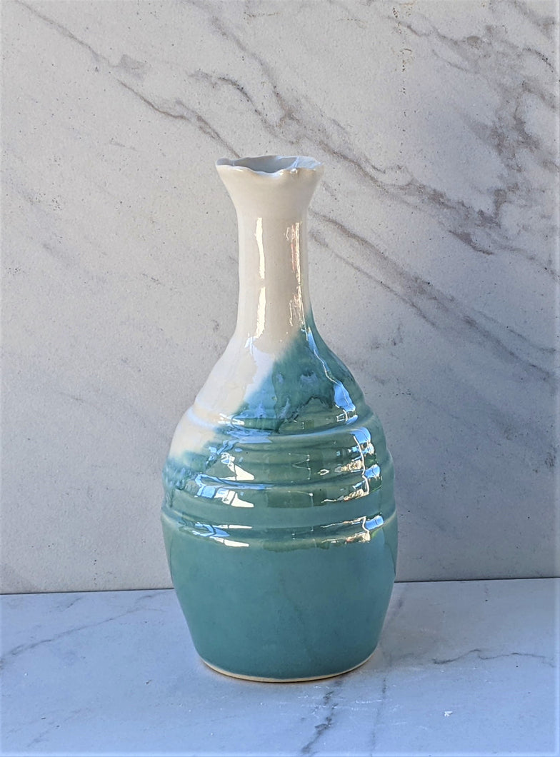 Small skinny neck vase with a flutted lip. Colors are robin's egg blue base with a white neck.