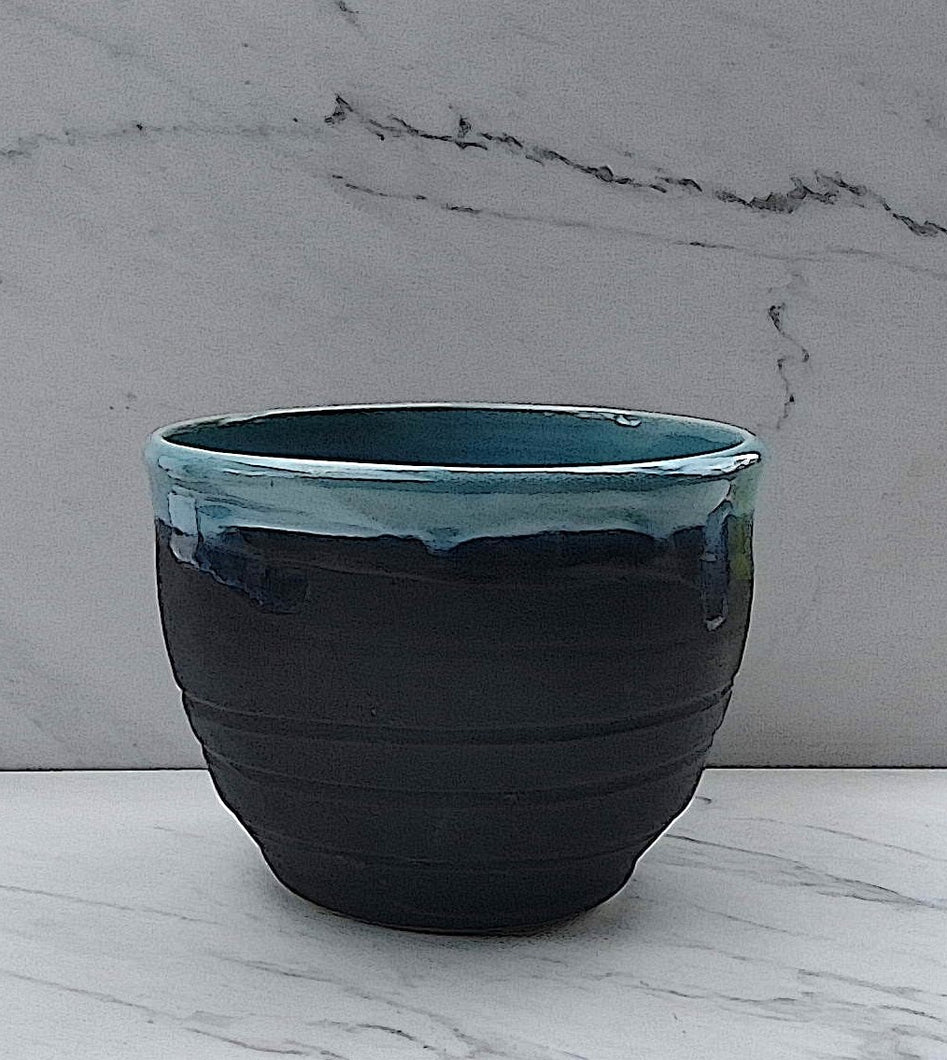 The outside of the bowl is matte black. The inside is glazed with a glossy Robin's Egg blue flowing over the top of the bowl.