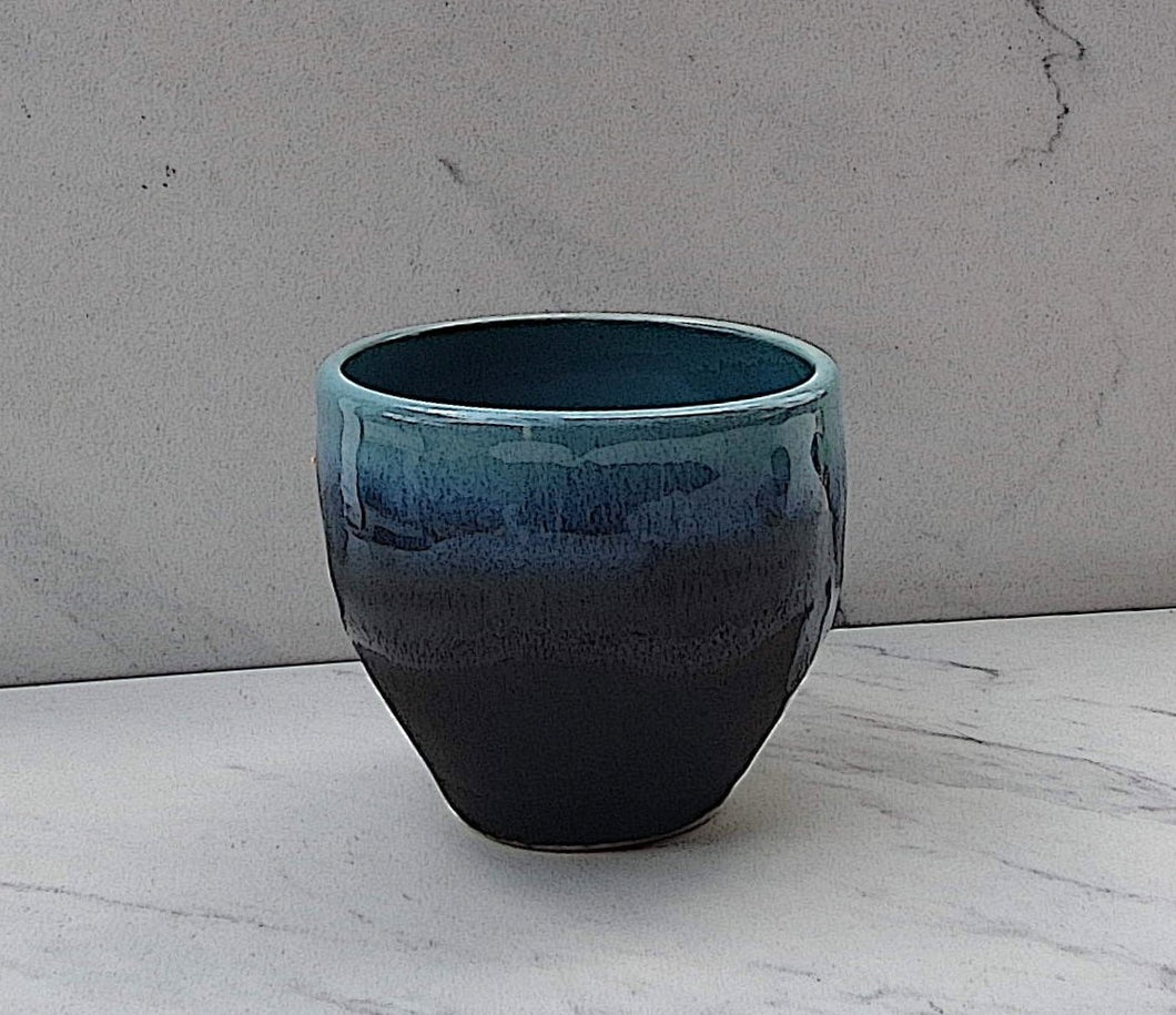 The outside of the bowl is matte black. The inside is glazed with a glossy Robin's Egg blue flowing over the top of the bowl. 