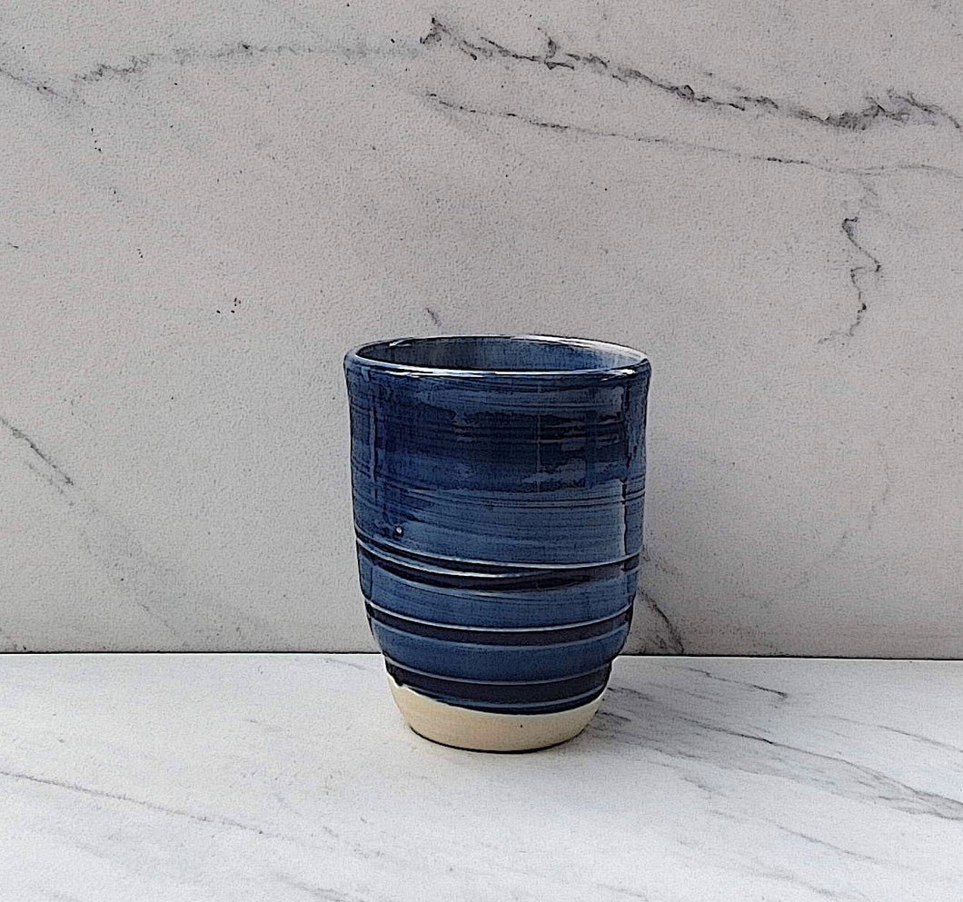 The outside of the tumbler has a royal blue glaze with a white glazed inside and an unglazed base.