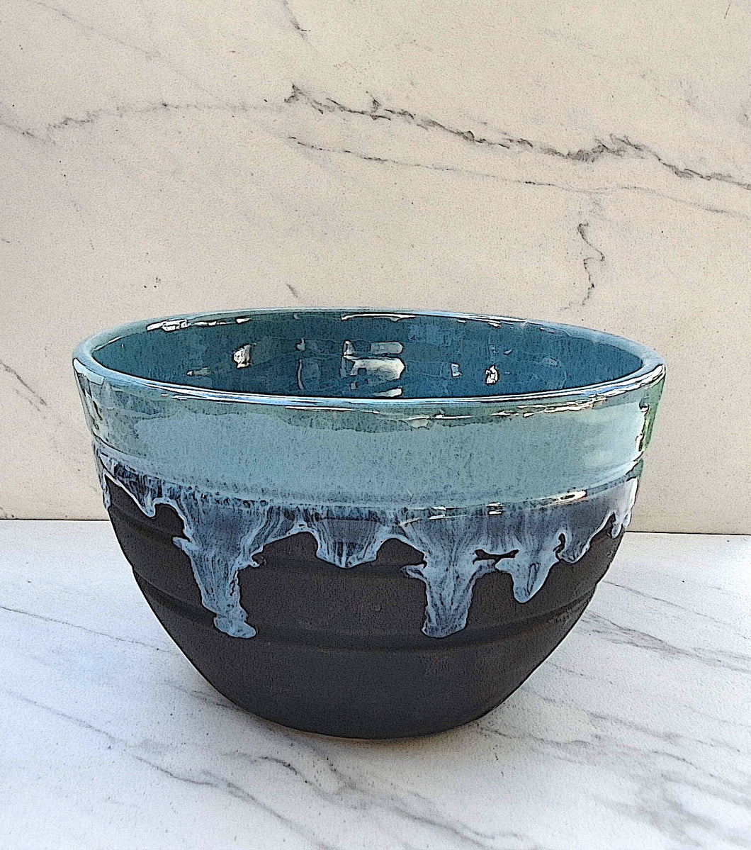 The outside of the bowl is matte black. The inside is glazed with a glossy Robin's Egg blue flowing over the top of the bowl. 