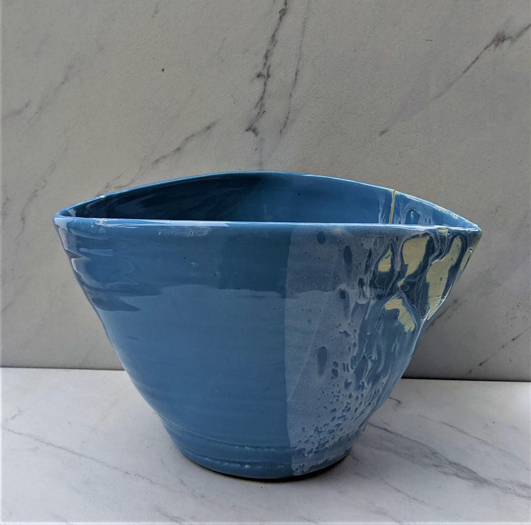 Blue glazed medium lemon-shaped pot with intermittent white glaze and rough clay. Pot does have a significant crack down the side