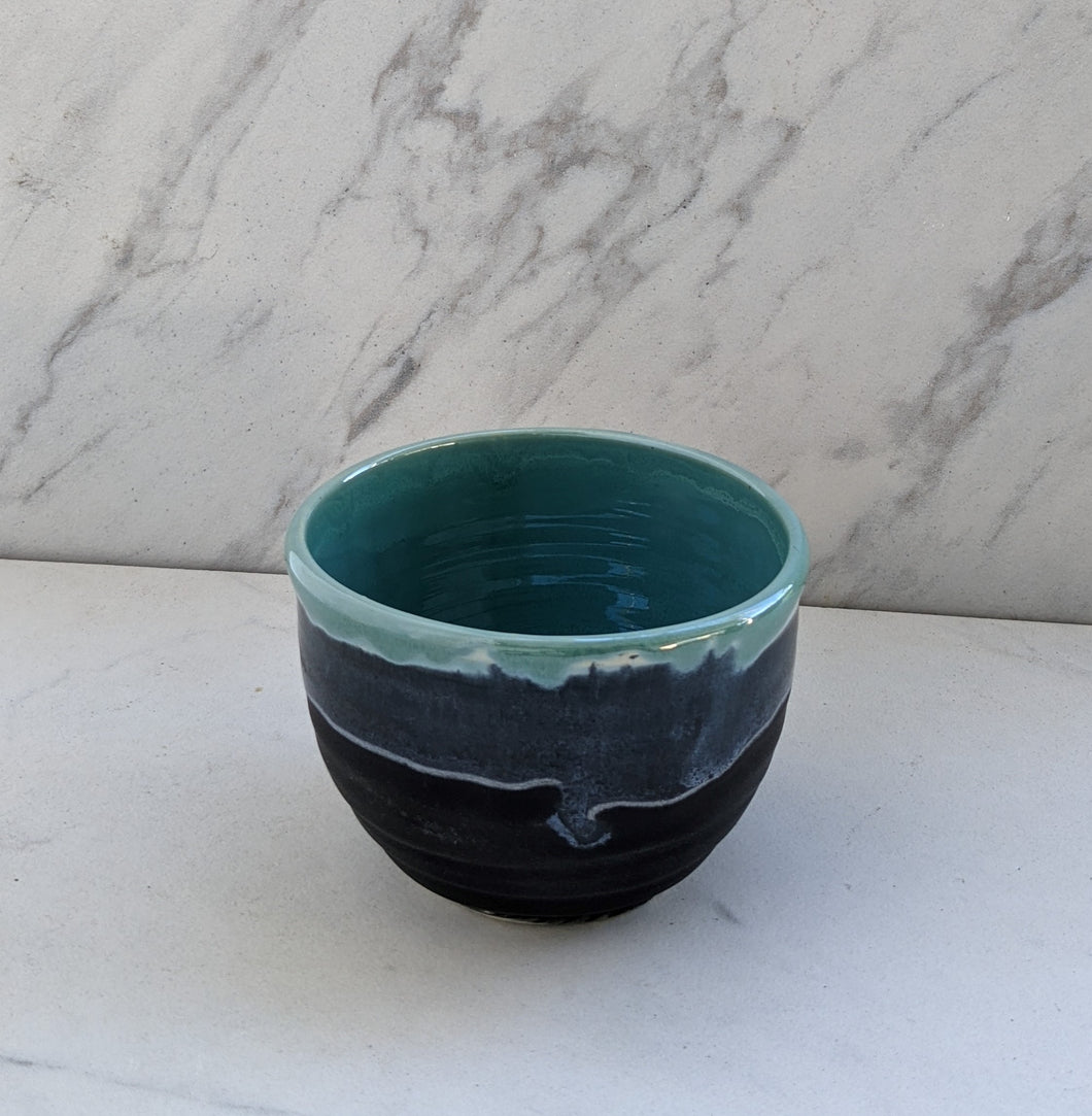 Small 8oz bowl of matte black base with robin's egg blue dripping over lip.